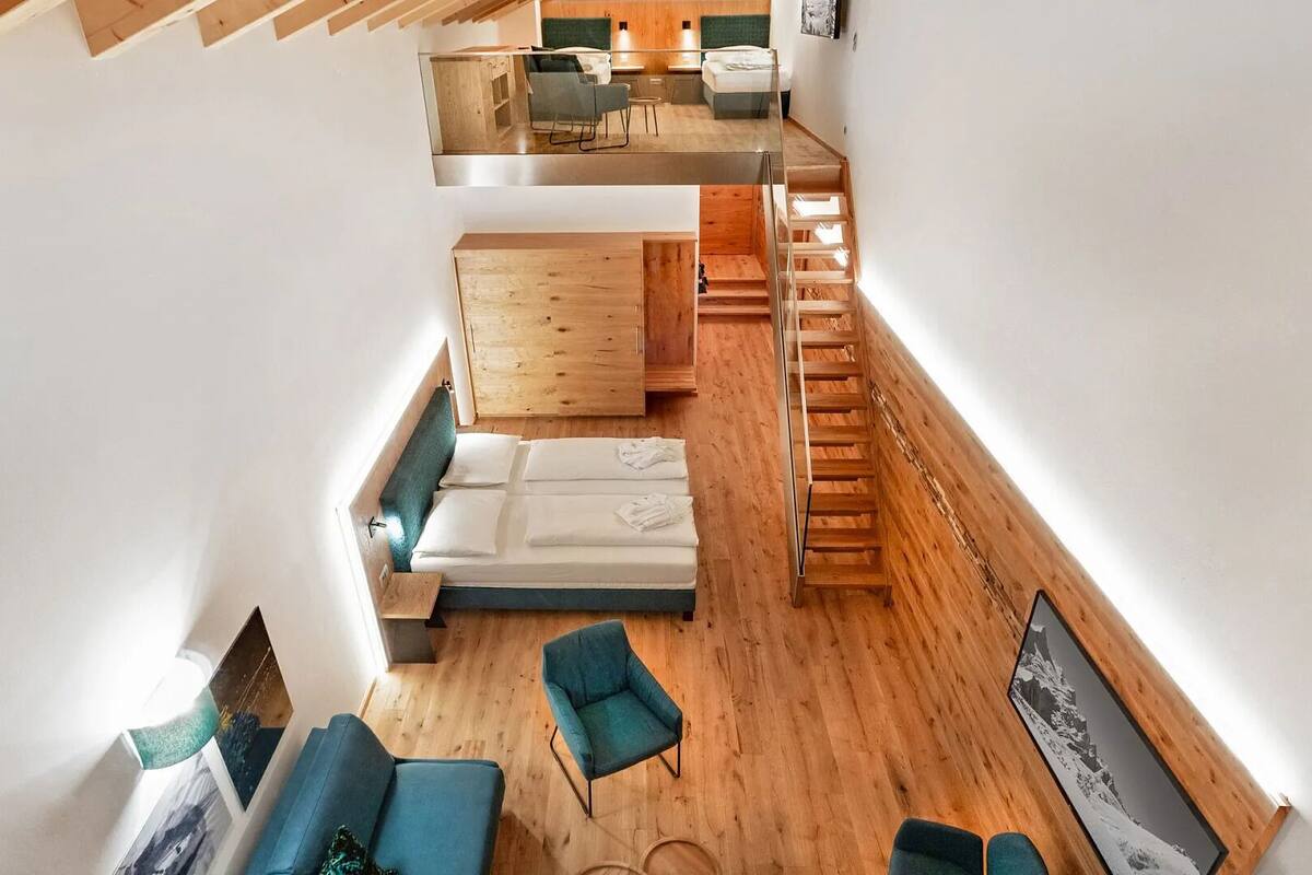 Un intérieur moderne avec une chambre à coucher de style loft, un coin salon avec un canapé et des fauteuils, et un escalier.