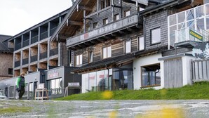 Un immeuble à plusieurs étages doté de balcons, une enseigne de restaurant et une personne qui marche devant.