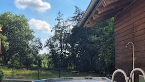 Una piscina fuori terra rotonda con rivestimento in pietra, circondata da un pontile in legno e una scala in metallo.