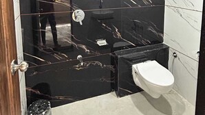 Een moderne badkamer met zwarte marmeren wanden, een wit toilet en een wastafel.
