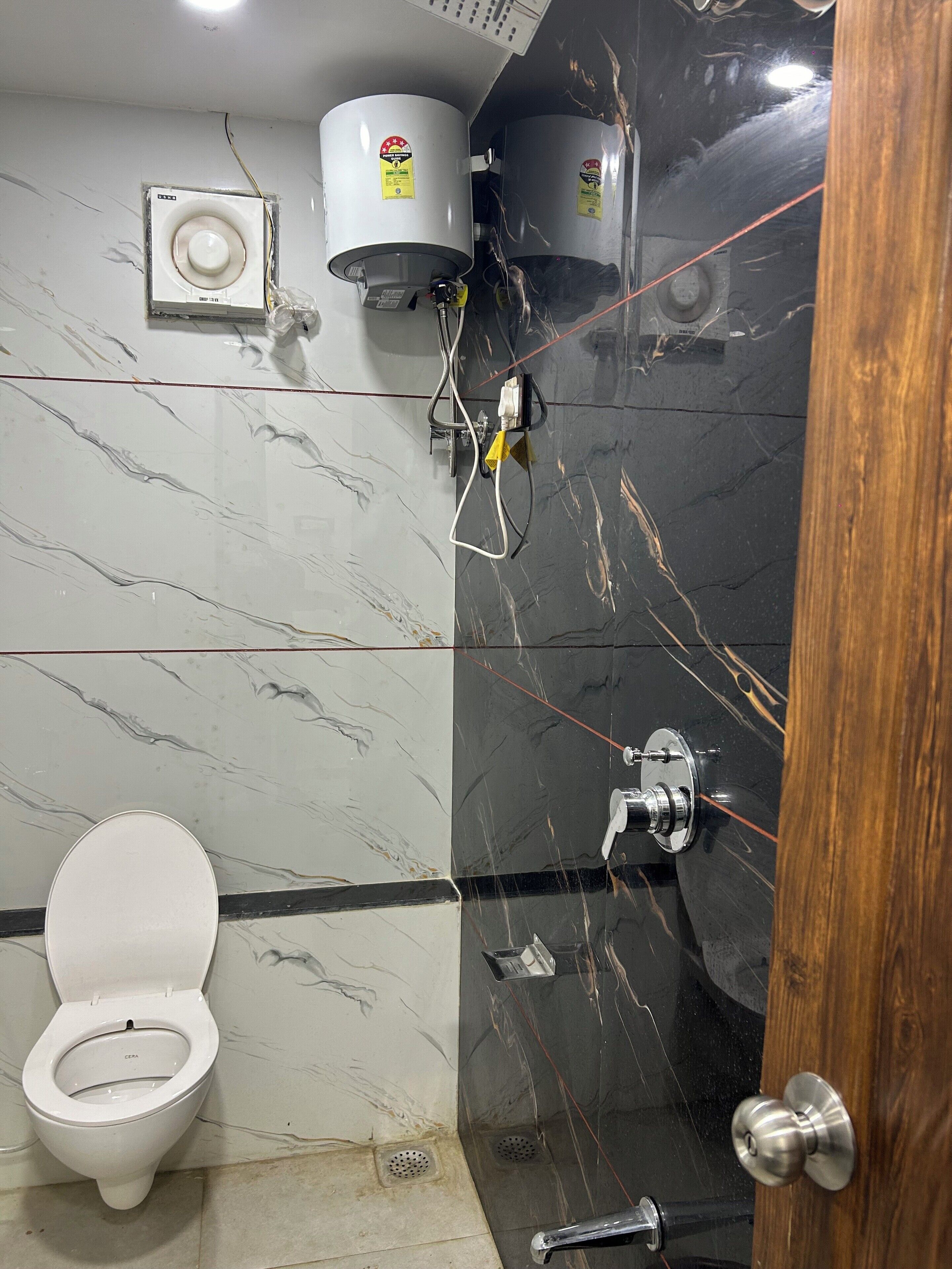 Een badkamer met toilet, boiler en douche.