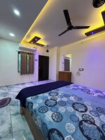 A bedroom with a bed, ceiling fan, air conditioning unit, and a door.