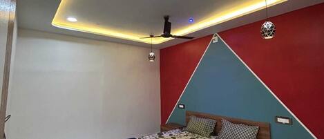 A bedroom with a bed, a nightstand, a ceiling fan, and a wall-mounted light fixture.