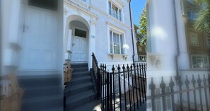 A white building with a black iron fence, a set of stairs, and a door. - Delightful 1BD Flat in Upper Holloway, N London (Greater London)