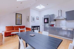 A modern kitchen with grey cabinets, a stainless steel range hood, and a built-in oven.