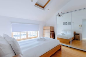 A modern bedroom with a large bed, a sliding glass door, and a skylight. - Delightful 1BD Flat in Upper Holloway, N London (Greater London)