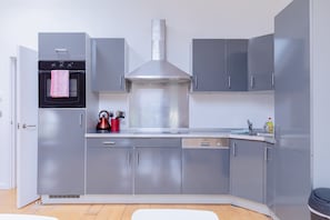 A modern kitchen with grey cabinets, a stainless steel range hood, a built-in oven, and a dishwasher. - Delightful 1BD Flat in Upper Holloway, N London (Greater London)