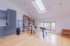 A spacious loft with a skylight, a kitchen area, a dining table with chairs, and a bookshelf. - Delightful 1BD Flat in Upper Holloway, N London (Greater London)