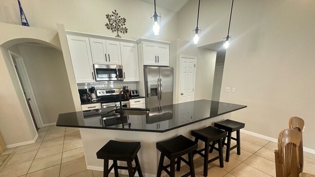 A modern kitchen with a large island, stainless steel appliances, and bar stools.