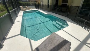 An indoor swimming pool with clear water, surrounded by a glass enclosure, and equipped with steps leading into the pool.