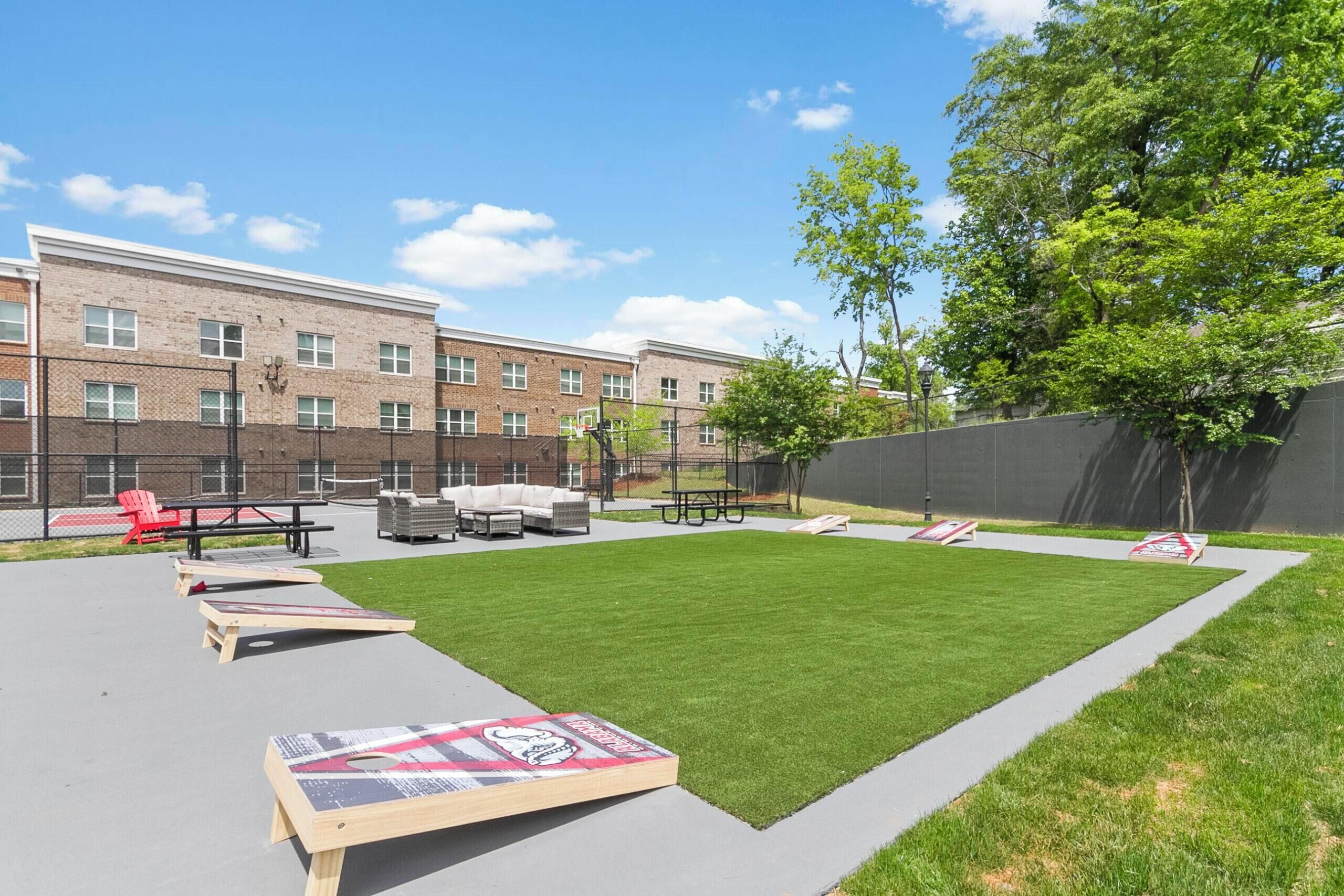 A courtyard with a lawn, picnic tables, and red chairs.