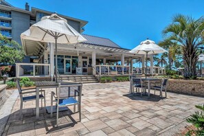 Un patio al aire libre con mesas, sillas, sombrillas y un edificio al fondo.