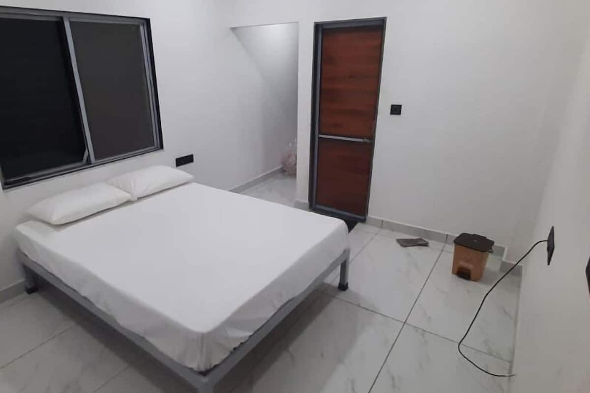 A bedroom with a bed, a window, a door, and a tiled floor.