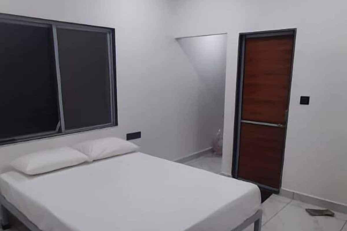 A bedroom with a bed, a ceiling fan, a window, and a door.