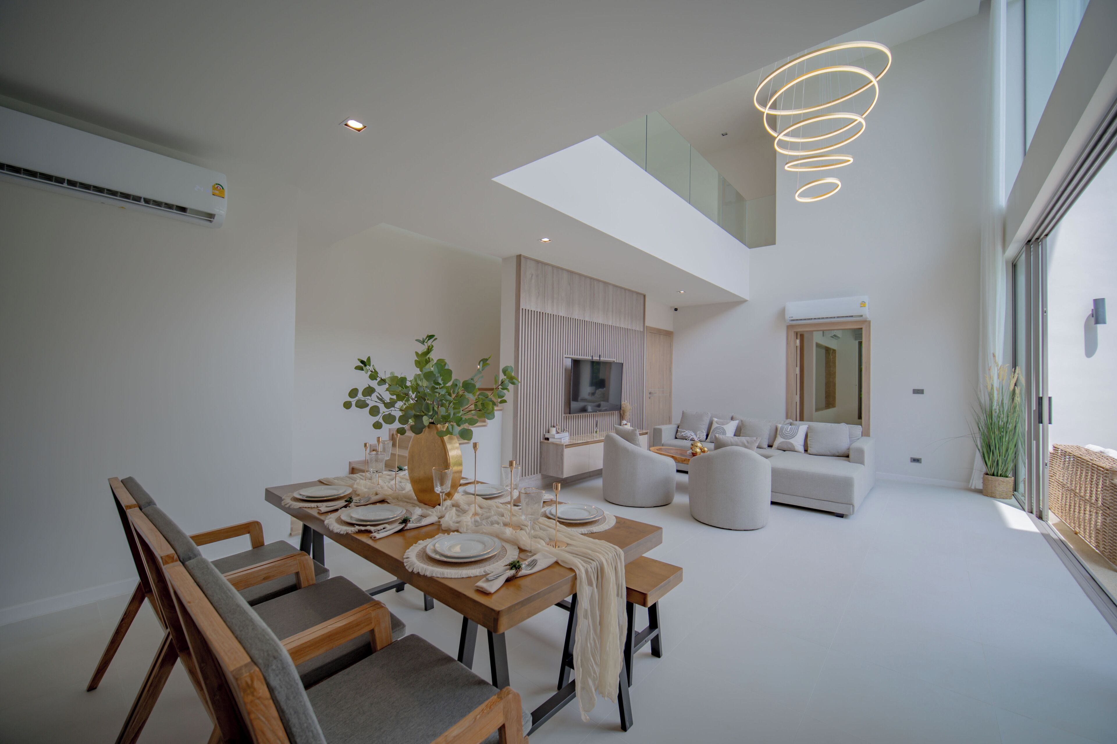 A modern living space with a dining area, a sofa set, and a TV.