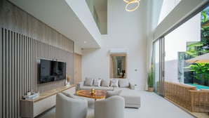 A modern living room with a flat-screen TV, a sofa, and a coffee table. - Zenithy 3BR Villa with Pool by NLA (Choeng Thale)