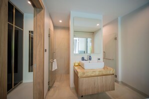 A modern bathroom with a large mirror, a sink, and a shower.