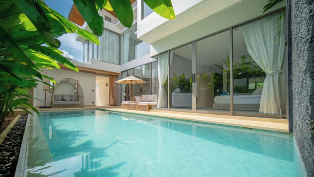 A modern pool area with clear water, a lounge chair, and a glass-enclosed room with a bed. - Zenithy 3BR Villa with Pool by NLA (Choeng Thale)