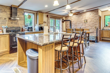 A modern kitchen with a central island, bar stools, and a view of the outdoors.