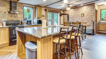 A modern kitchen with a central island, bar stools, and a view of the outdoors.