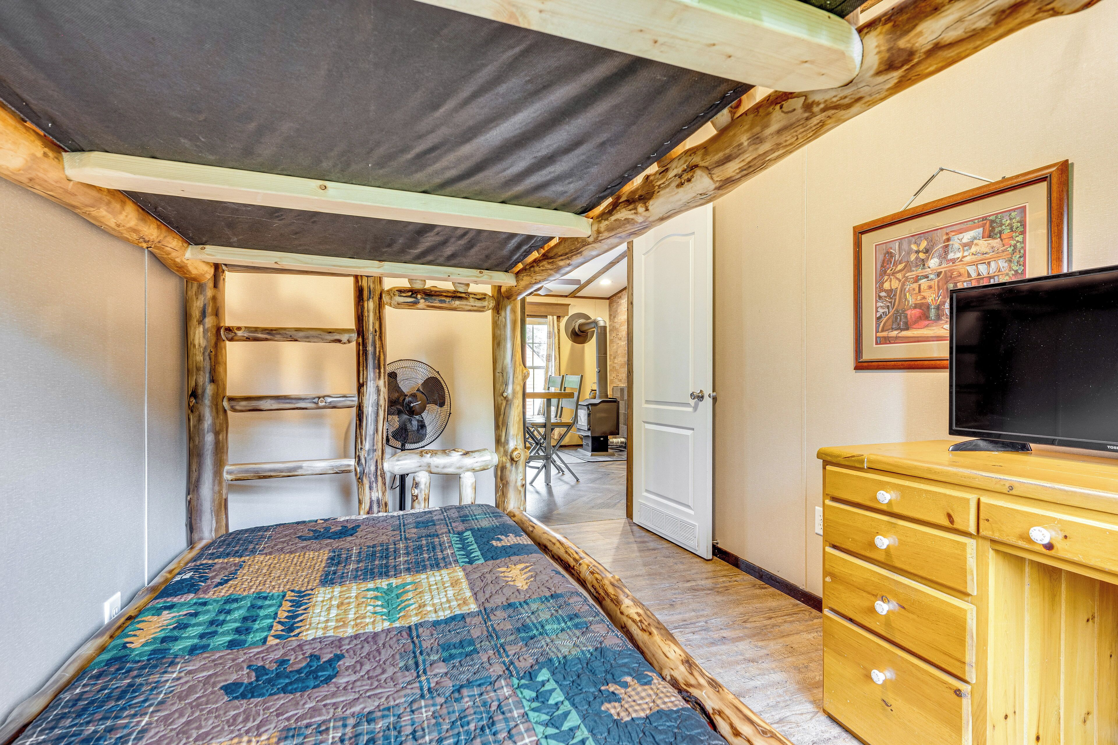 A room with a bed, wooden dresser, and a television.