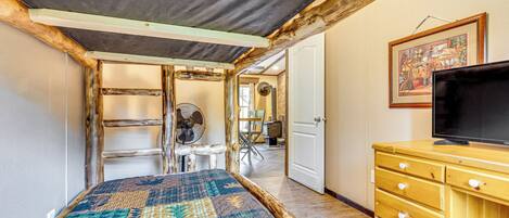 A room with a bed, wooden dresser, and a television.