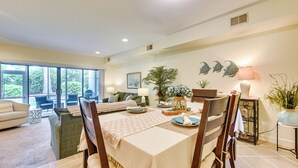 Un coin repas avec une table dressée pour quatre personnes, entourée de chaises, d’un canapé et d’une table basse.