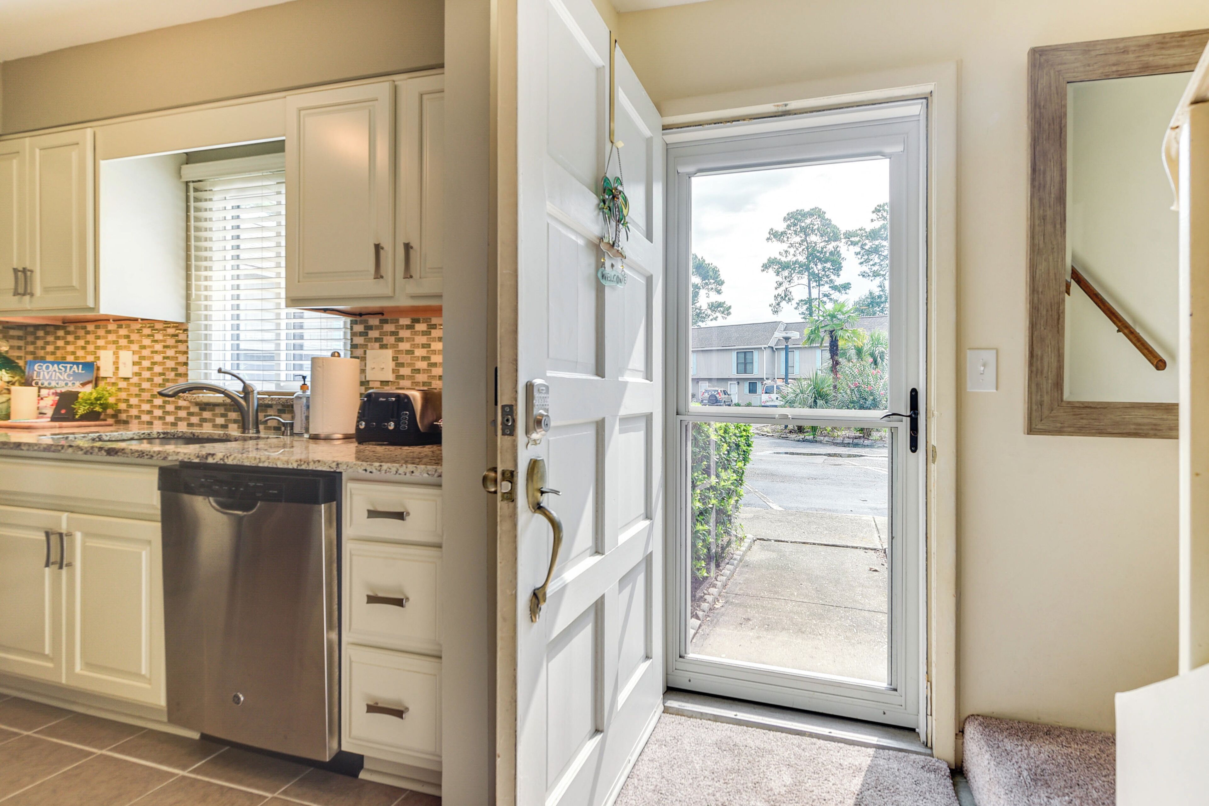 A kitchen with white cabinets, a dishwasher, and a countertop with a coffee maker.
