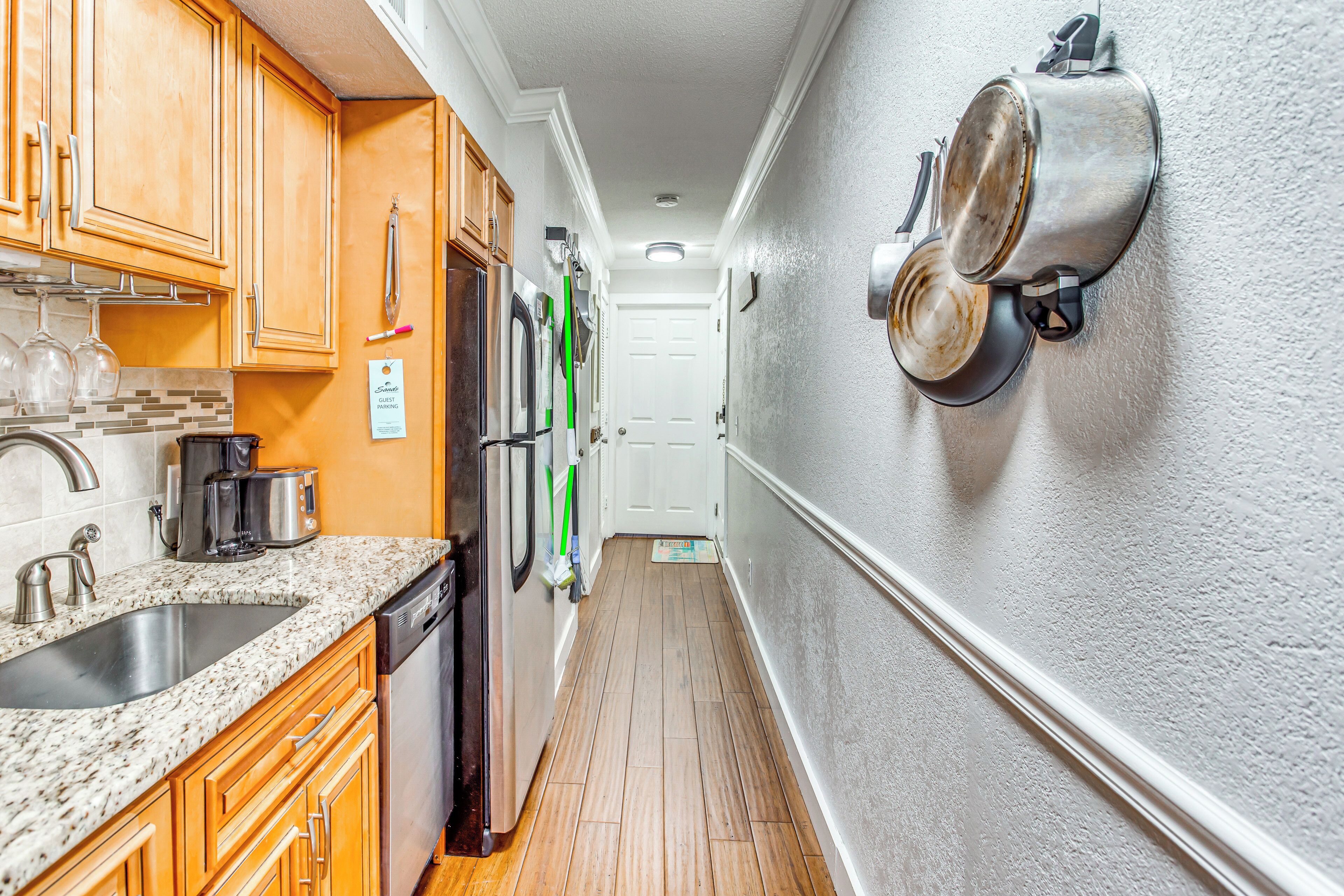 A narrow kitchen with wooden cabinets, a granite countertop, and stainless steel appliances.