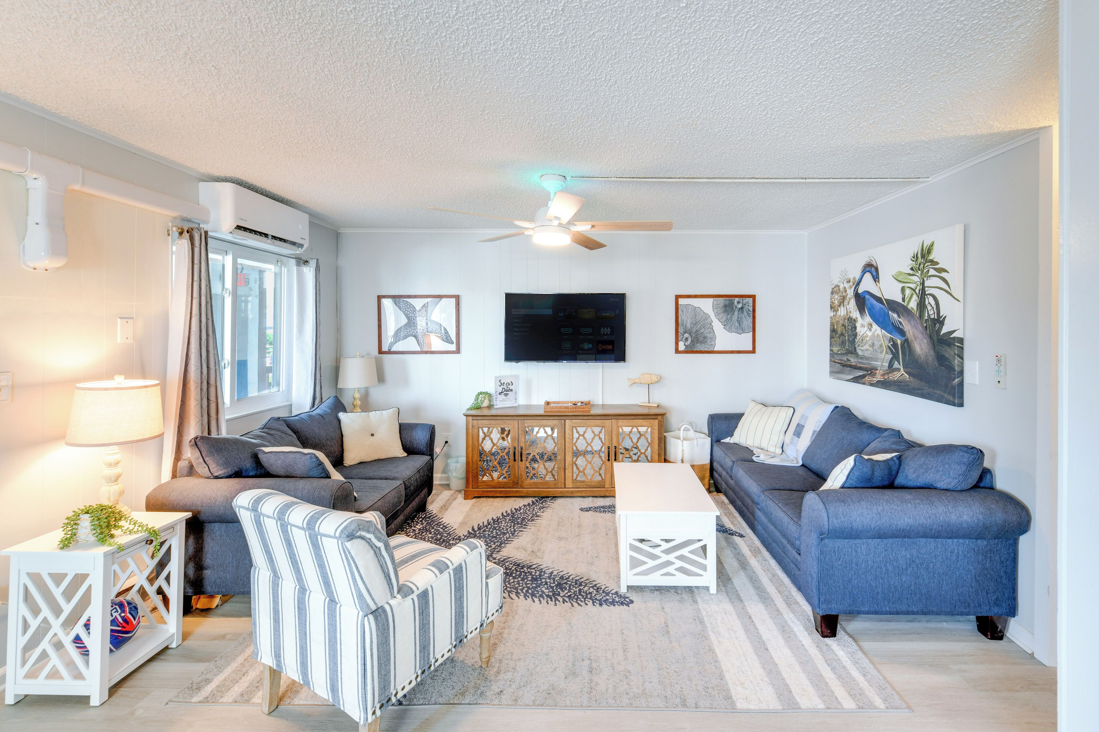 Een moderne woonkamer met een bank, fauteuil, salontafel en een televisie op een houten kast.