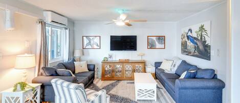 A modern living room with a sofa, armchair, coffee table, and a TV on a wooden cabinet.