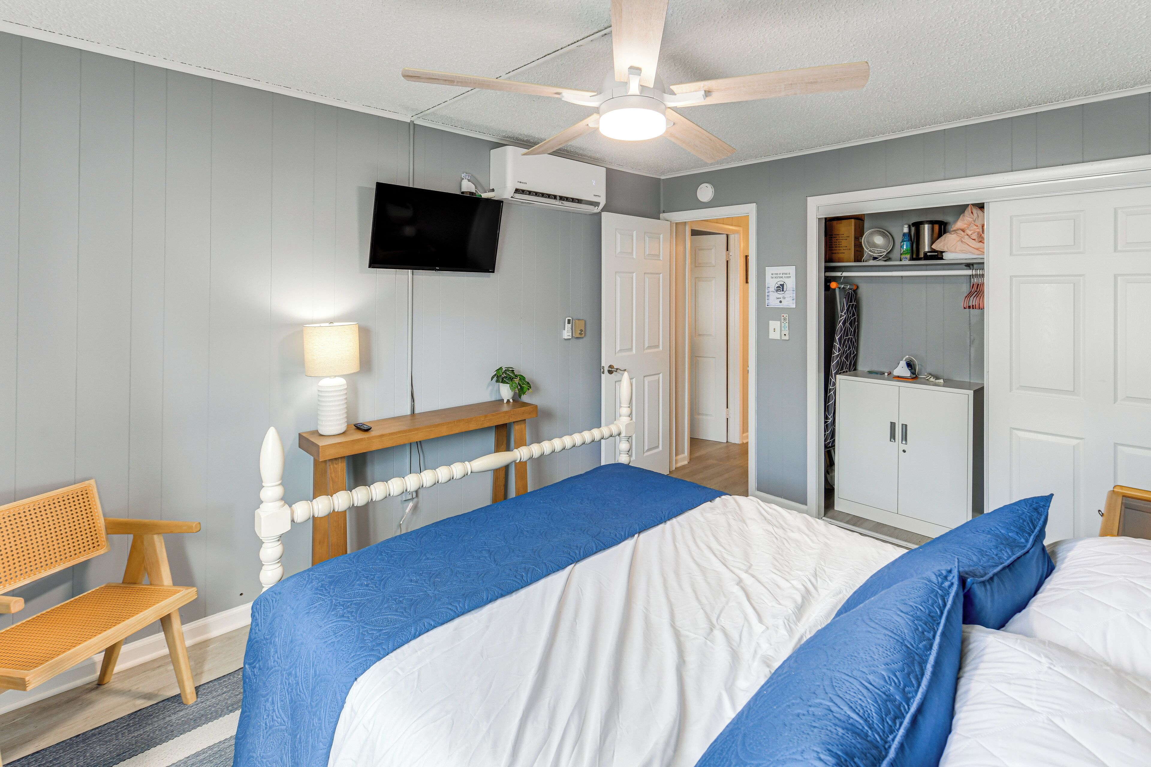 A bedroom with a bed, a desk, a chair, a TV, and a wardrobe.