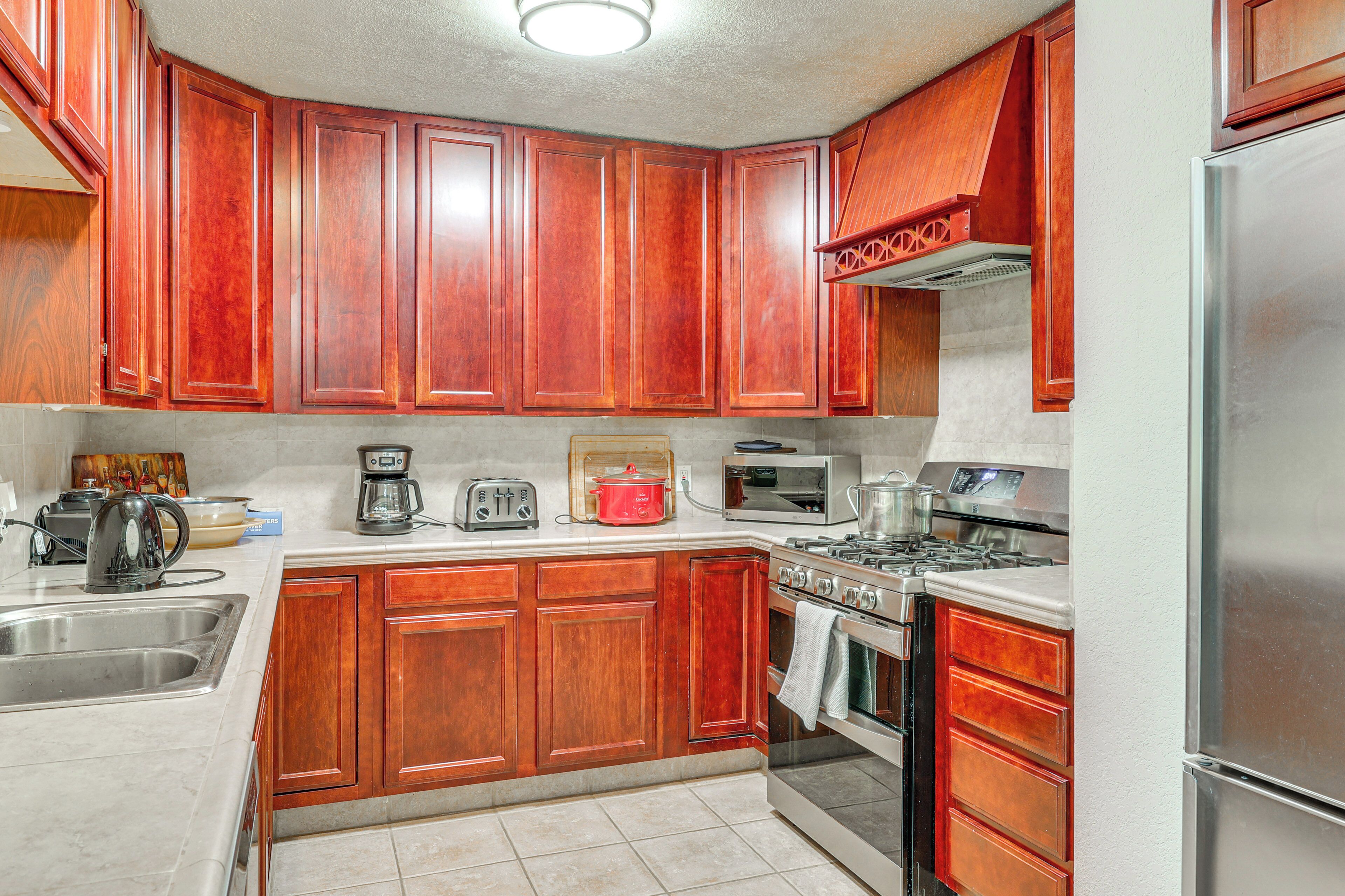 A kitchen with wooden cabinets, a stainless steel refrigerator, a stove, and a microwave.