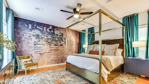 Una cama con dosel, un cabecero, un ventilador de techo y un mural grande en la pared.
