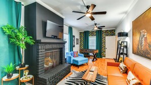 Una sala de estar con chimenea, sofá y televisor montado en la pared.