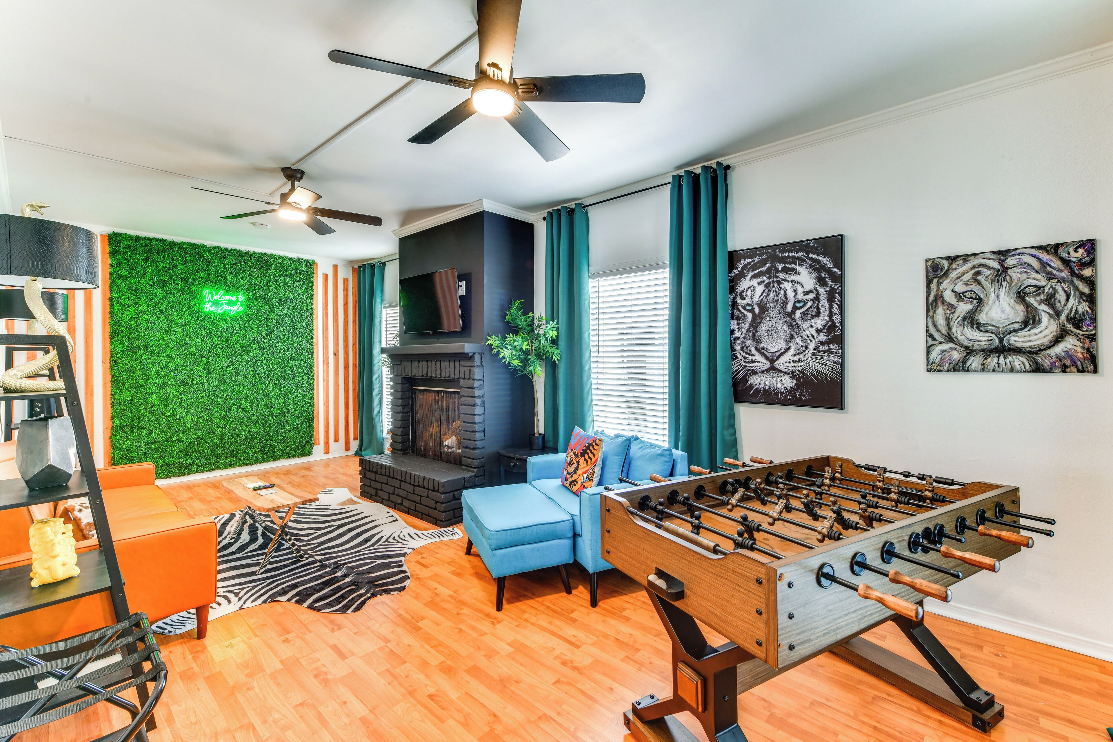 Una sala de estar moderna con una mesa de fútbol de mesa, una chimenea y una pared verde con un letrero de neón.