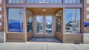 A building entrance with a glass door, a sign indicating units for sale, and a view of the street outside. - Dtwn Knoxville Studio Half-mi to Market Square! (Knoxville)