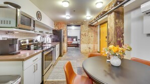A compact kitchen with modern appliances, a dining area with a table and chairs, and a visible bedroom with a bed and a door leading to another room. - Dtwn Knoxville Studio Half-mi to Market Square! (Knoxville)