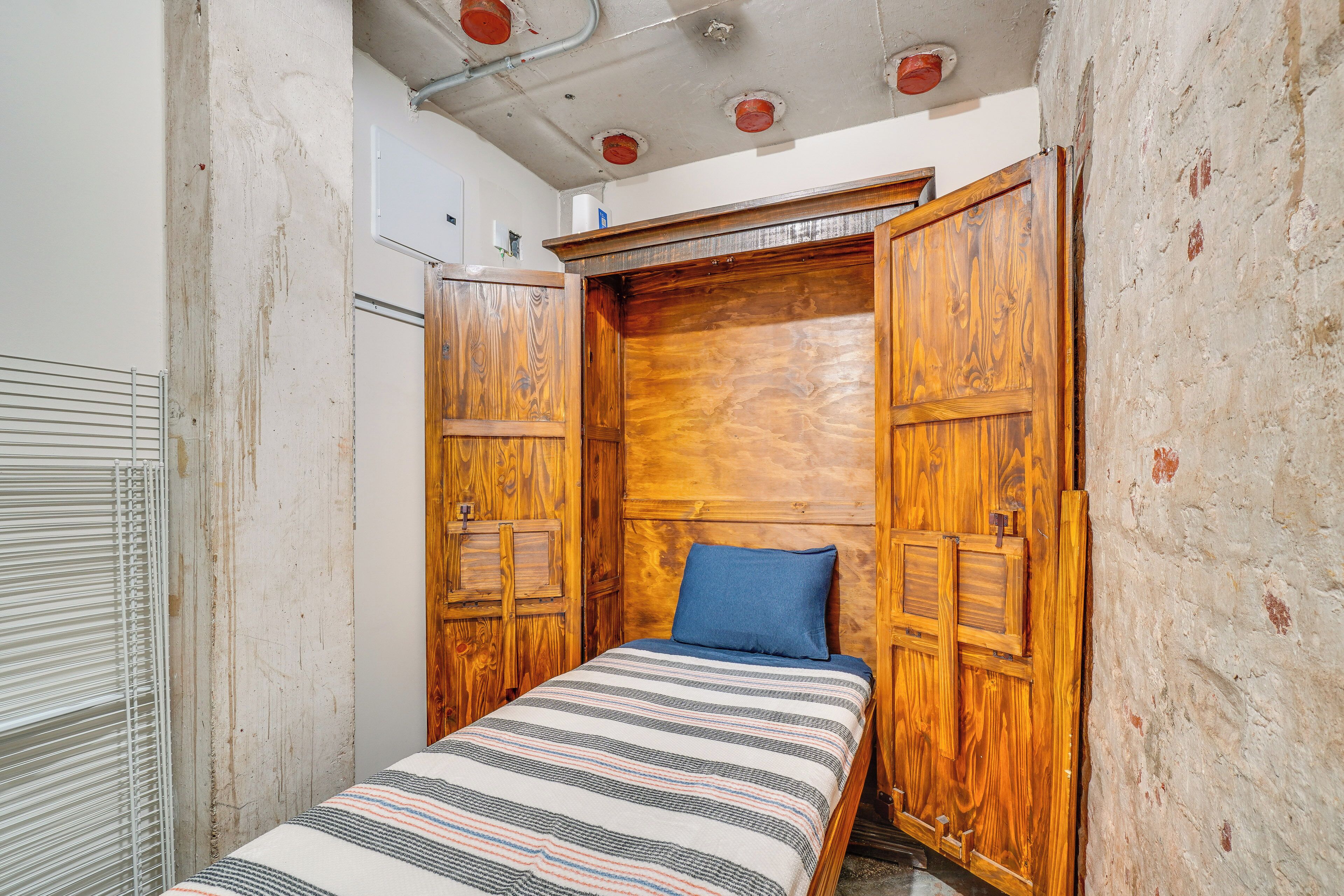 Um quarto pequeno e estreito com uma cama, guarda-roupa de madeira e um radiador.