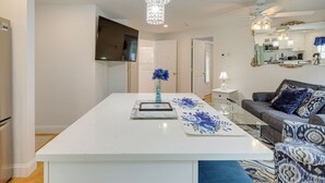Une cuisine moderne avec des plans de travail blancs, un îlot central et un lustre.
