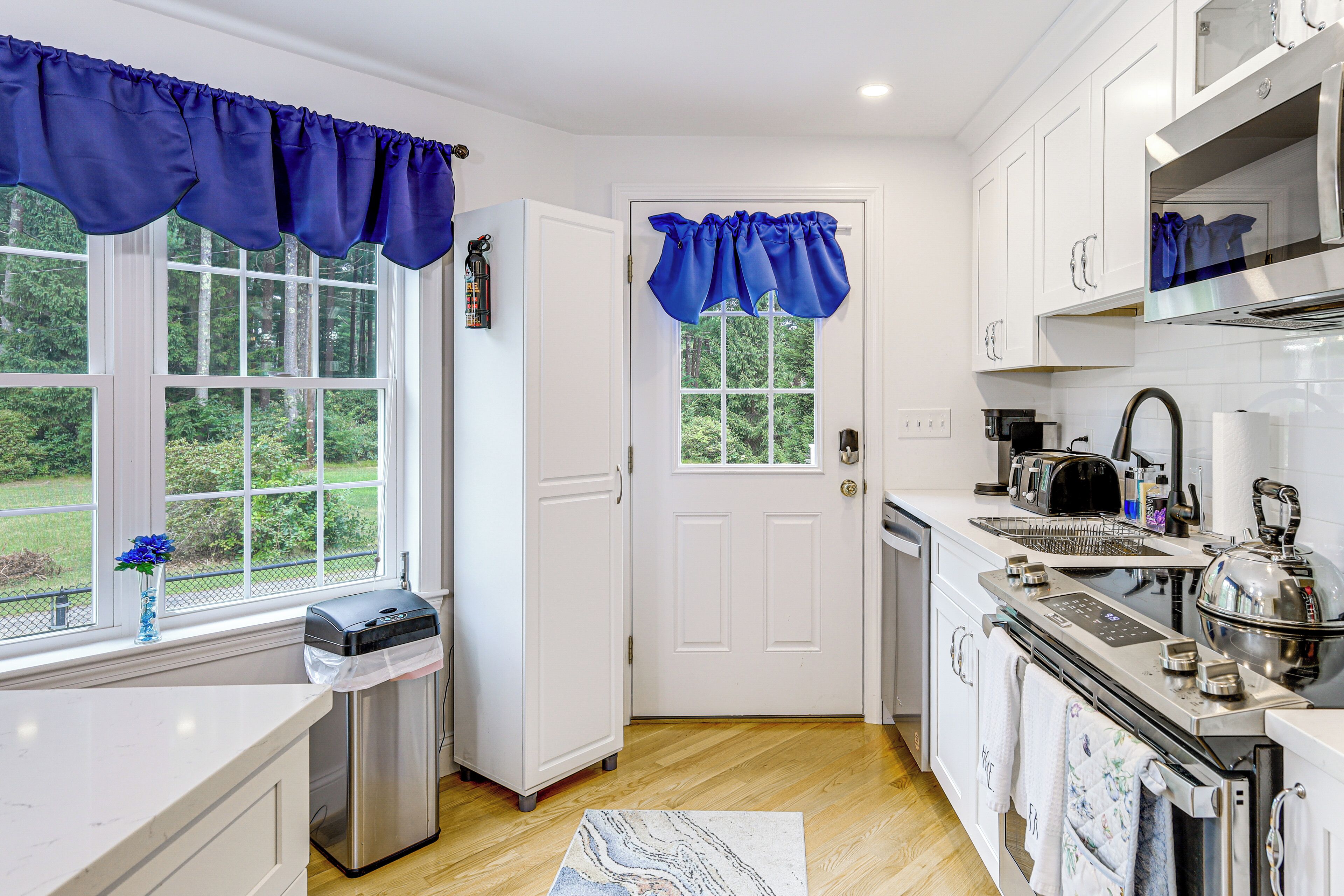 A modern kitchen with white cabinets, a stainless steel refrigerator, a dishwasher, and a stove.