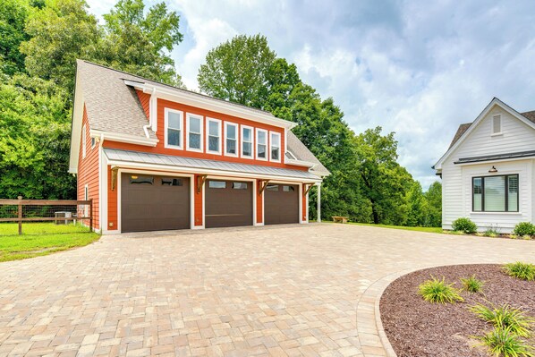 Ein zweistöckiges Haus mit Garage, gepflasterter Auffahrt und angelegtem Garten.