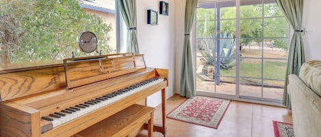 A piano in a room with a large window, a couch, and a rug.