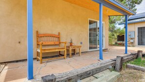 A covered patio with a wooden bench and table, a potted plant, and a stone floor. - Las Cruces Studio ~ 3 Mi to Nmsu! (Las Cruces)