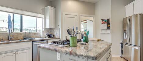A modern kitchen with white cabinets, granite countertops, and stainless steel appliances.