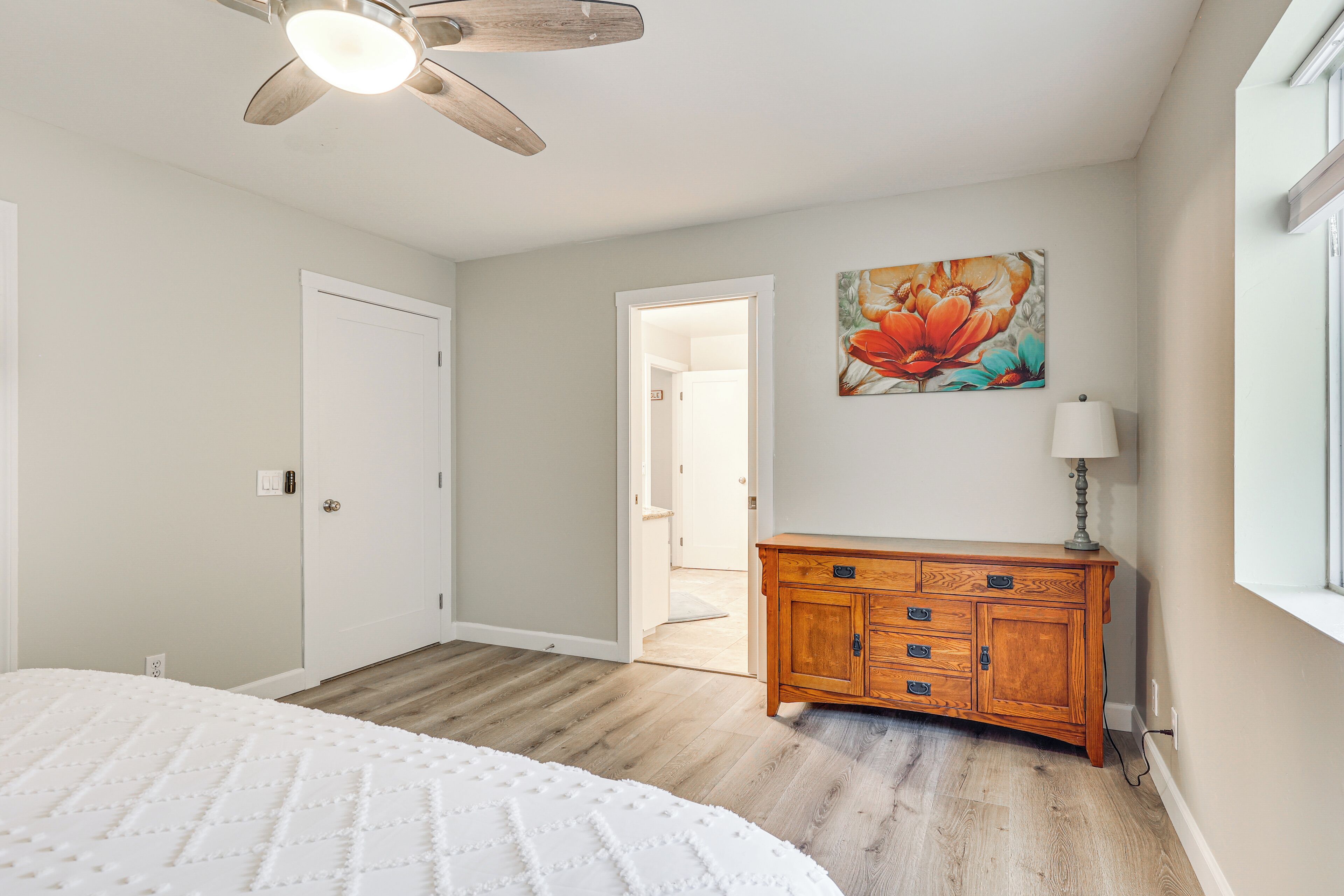 A bedroom with a bed, wooden dresser, and a ceiling fan.