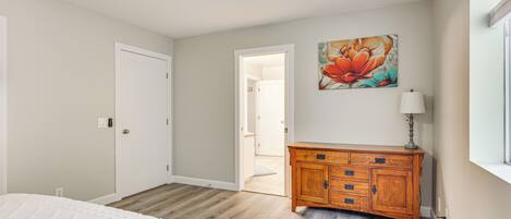 A bedroom with a bed, wooden dresser, and a ceiling fan.