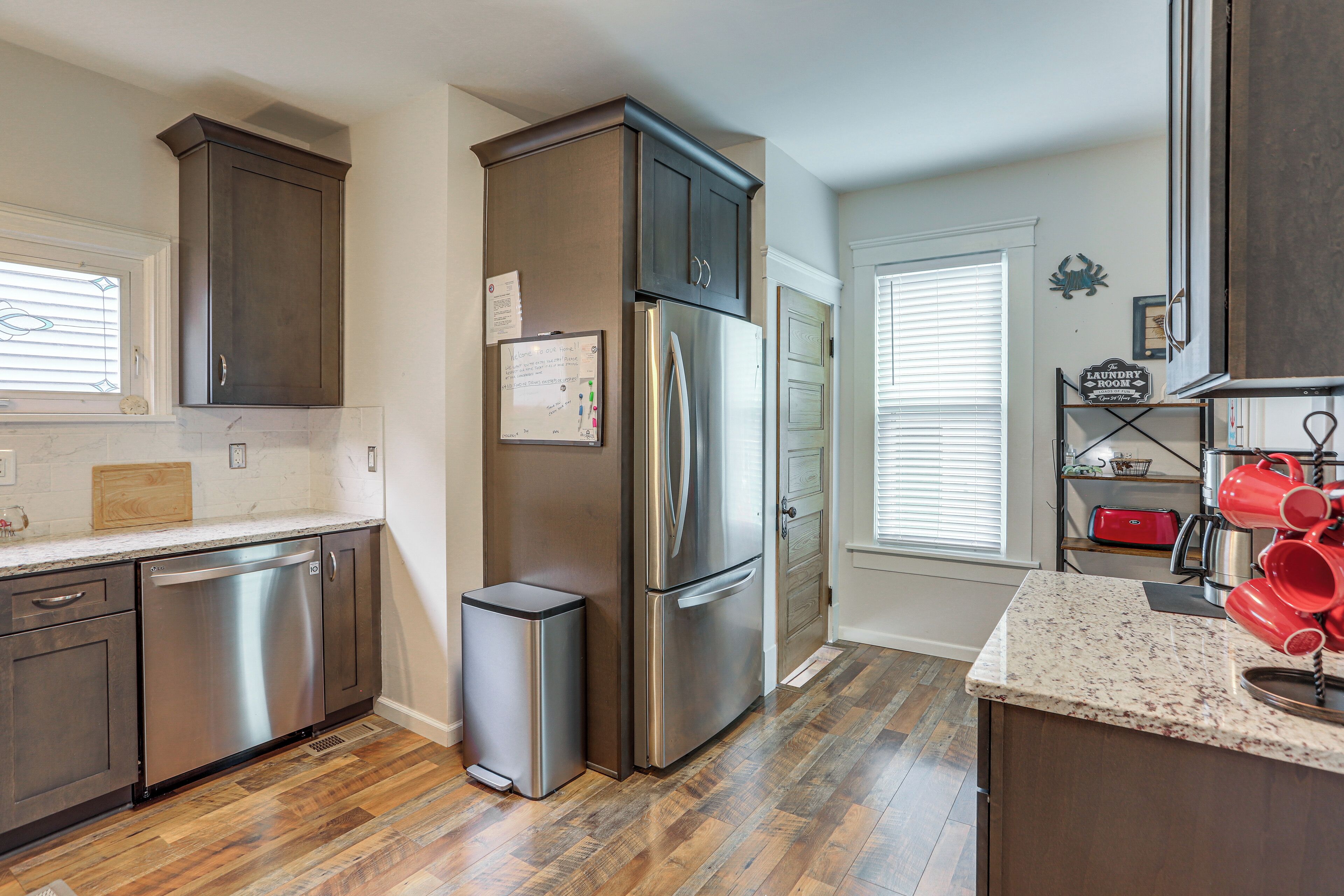 A modern kitchen with stainless steel appliances, wooden flooring, and a granite countertop.