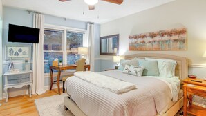 A bedroom with a large bed, a ceiling fan, a TV, and a window with curtains. - Blue Ridge Mtn Retreat: Porches & Creek Access (Hendersonville)