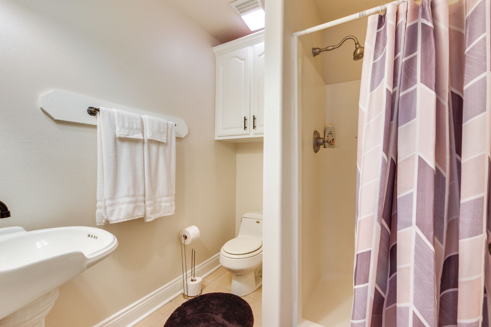 Un baño con lavamanos, inodoro y cortina de ducha.